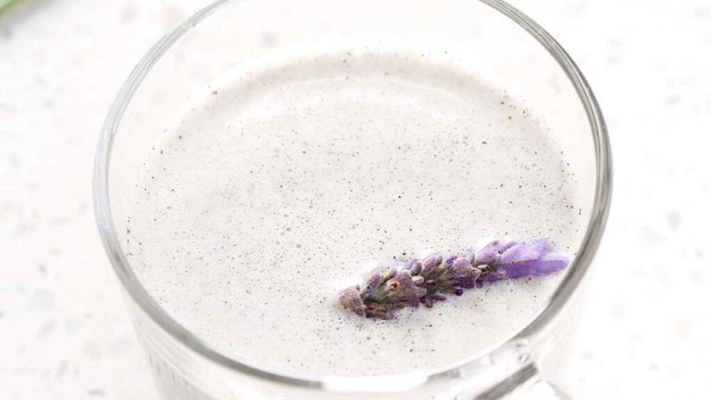 A closeup of a glass mug filled with lavender milk tea.