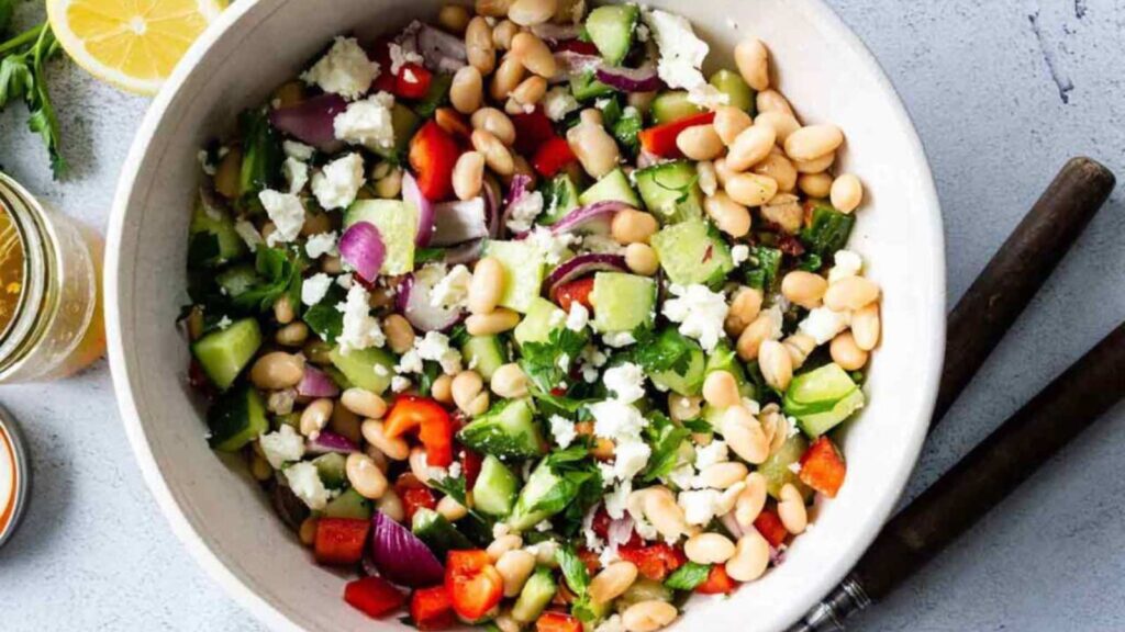 A large, white serving bowl filled with Mediterranean beans salad.