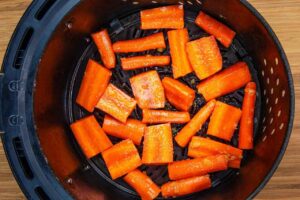 Raw carrots in an air fryer basket.