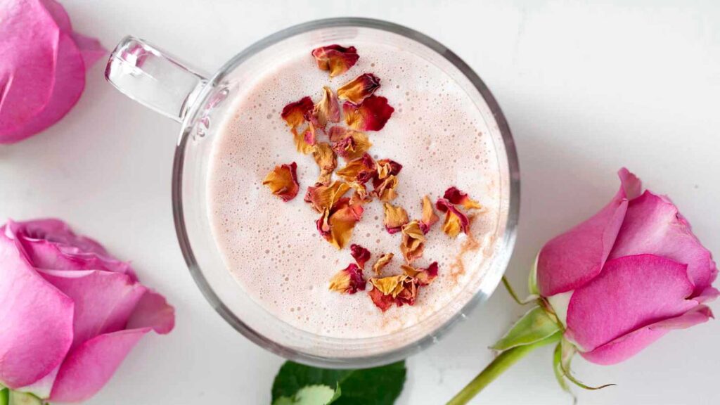 An overhead view of a rose latte garnished with dried rose petals.