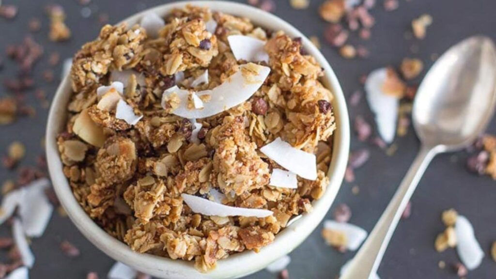 A white bowl filled with Gluten-Free & Low FODMAP Chocolate Coconut Granola.