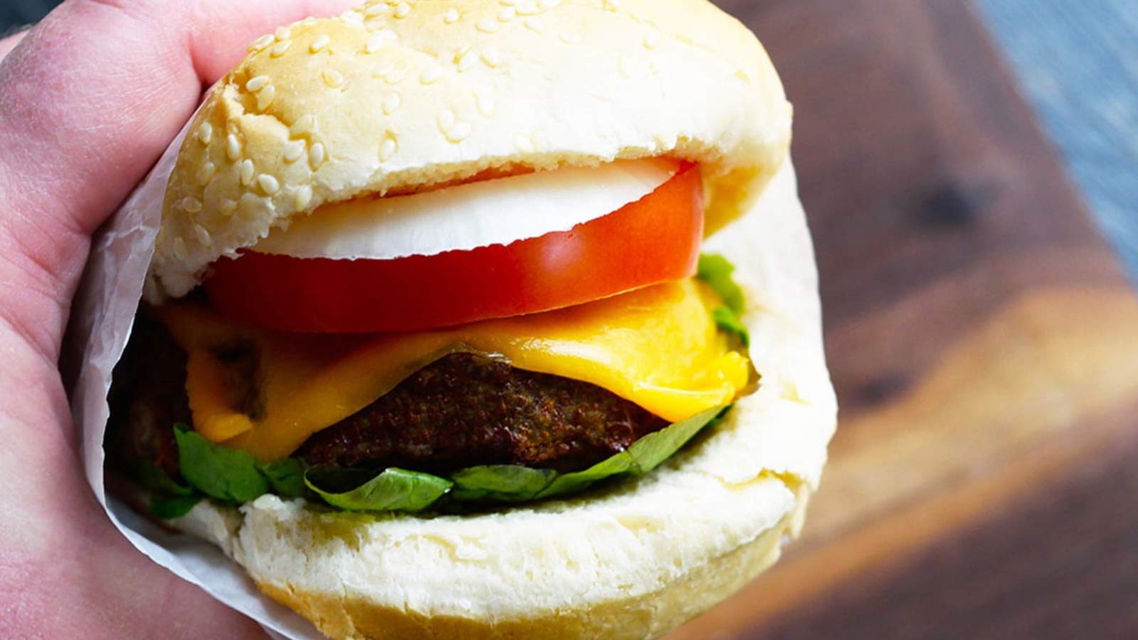 A hand holds an Air Fryer Turkey Burger wrapped in parchment.
