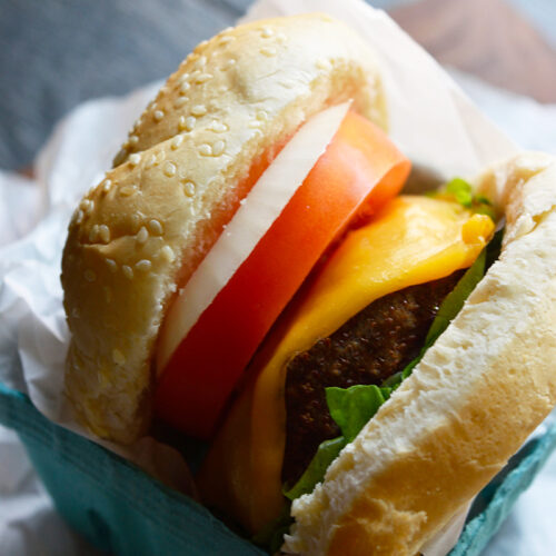 A parchment-wrapped turkey burger sitting in a paper carton.