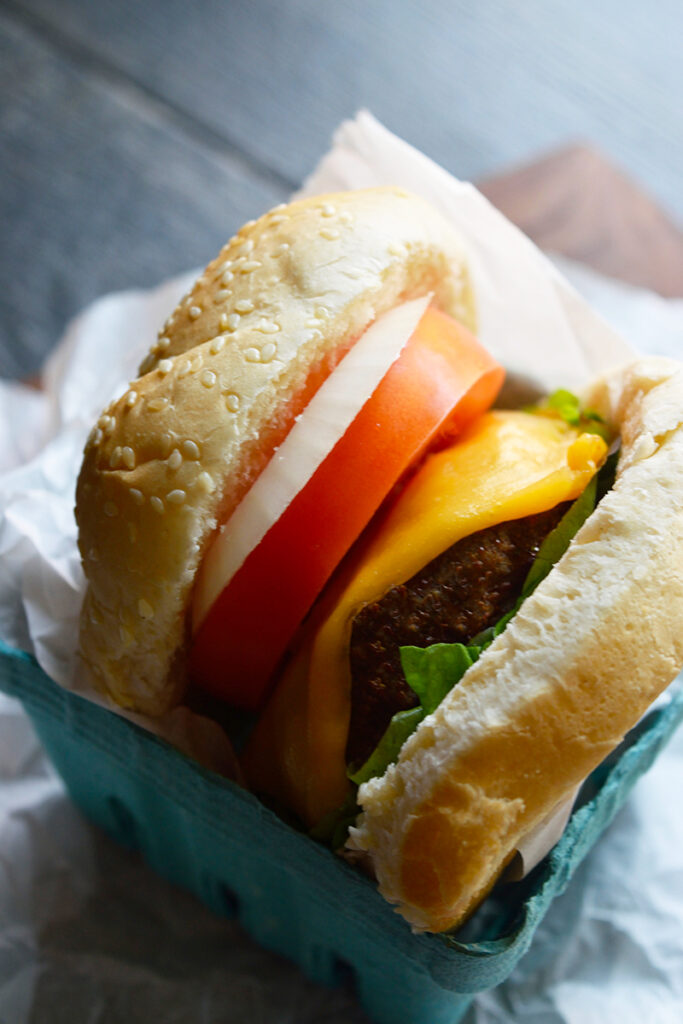 A parchment-wrapped turkey burger sitting in a paper carton.