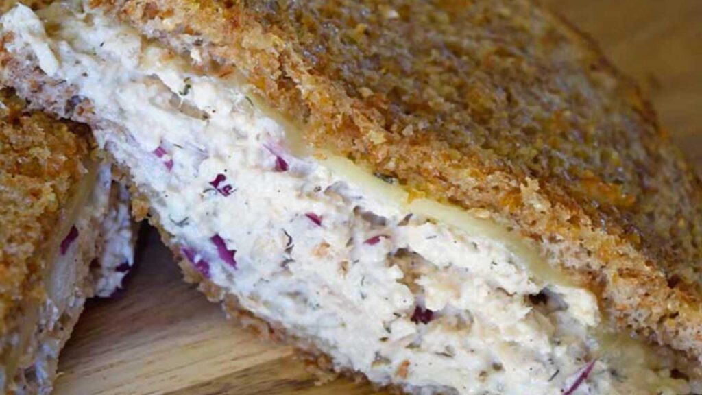 A closeup of a half of an air fryer tuna melt sandwich on a cutting board.