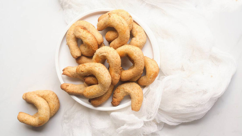 Almond Horns on a white plate which sits on a white background.