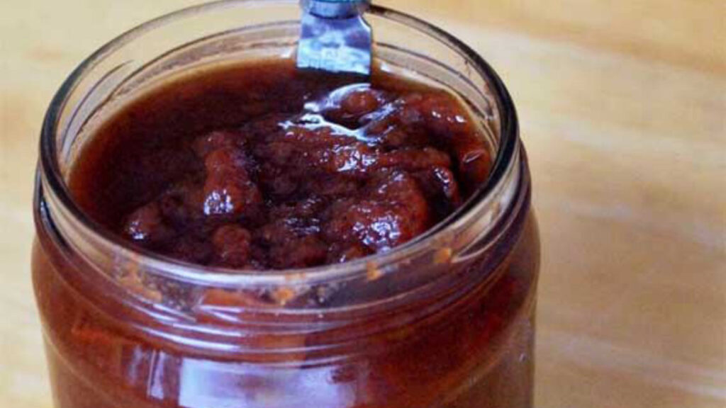 A closeup of an open jar of apple butter.