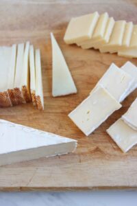 Various cheeses sliced to place on a charcuterie board.