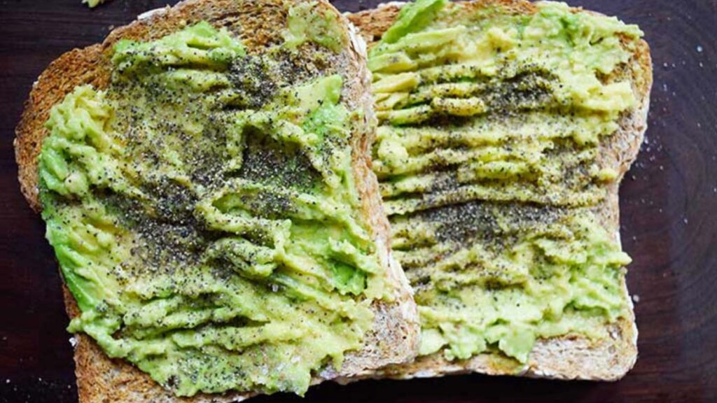 Two slices of avocado toast on a dark wood background.