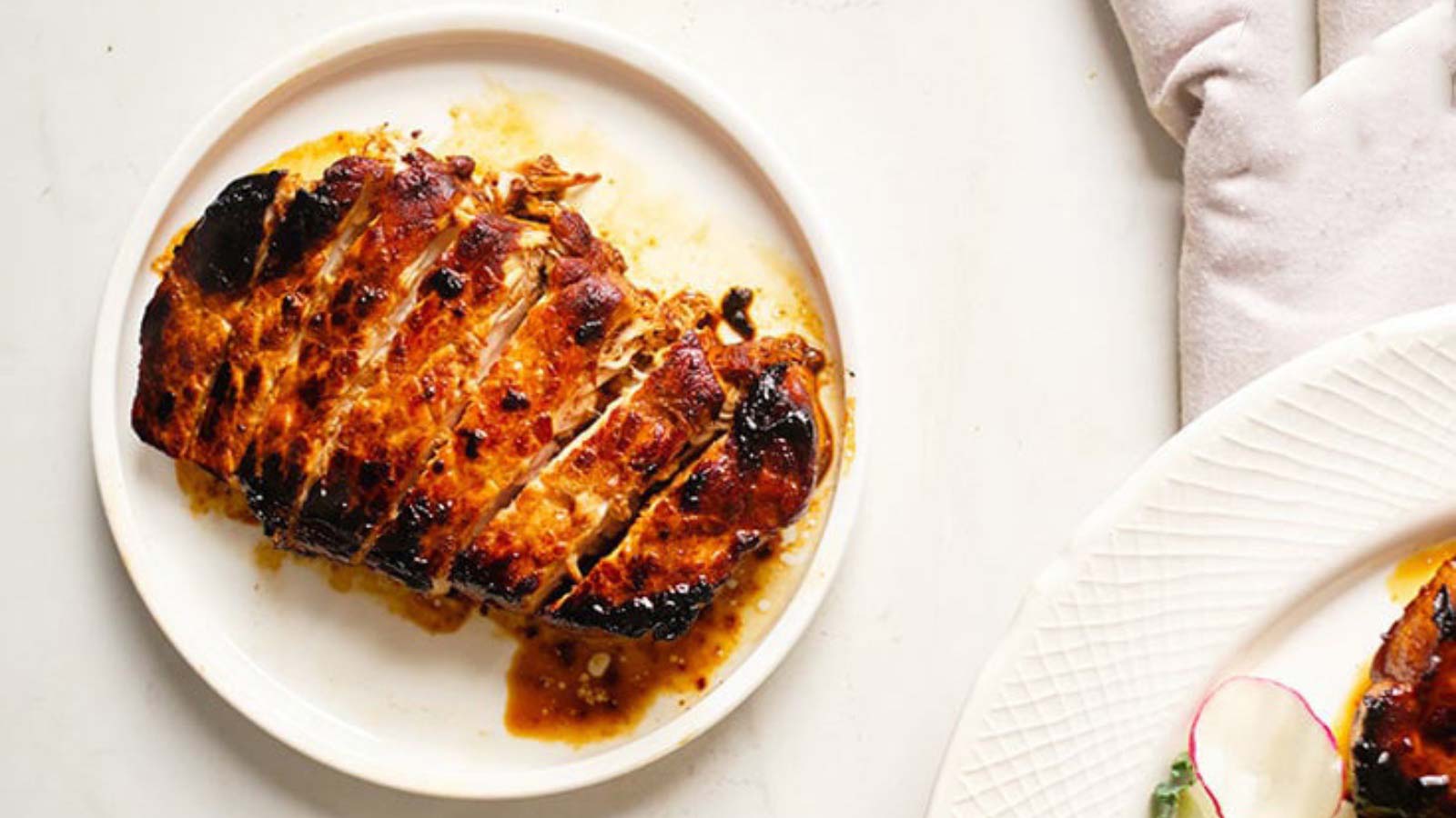 A cooked Balsamic Pork Chop on a white plate, cut and ready to enjoy.