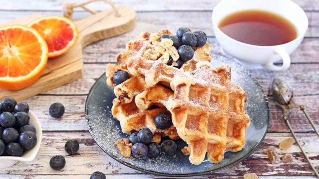 A plate of Belgian waffles with fresh blueberries on top.