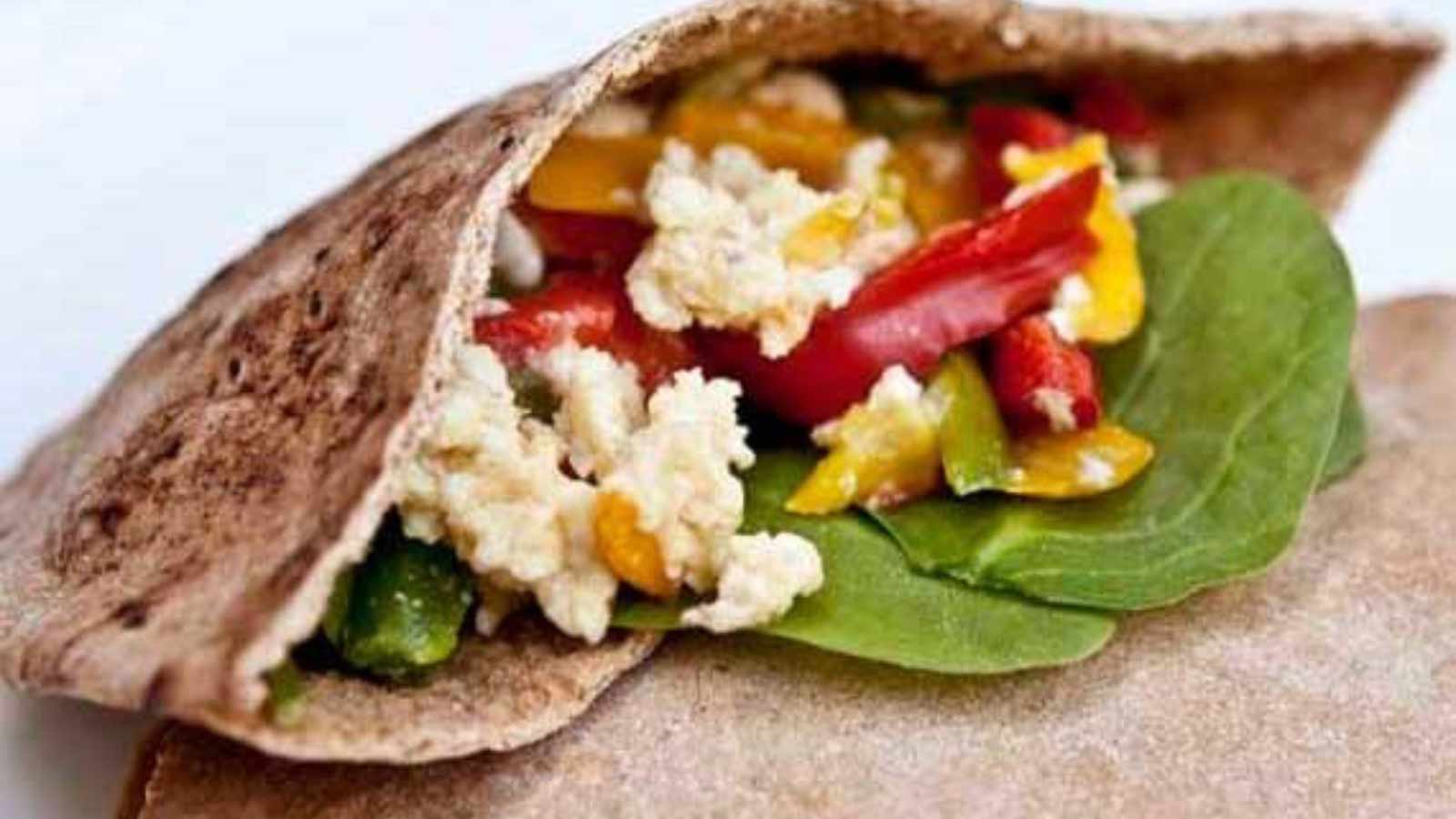 An open pita with eggs, bell peppers and fresh spinach stuffed inside.