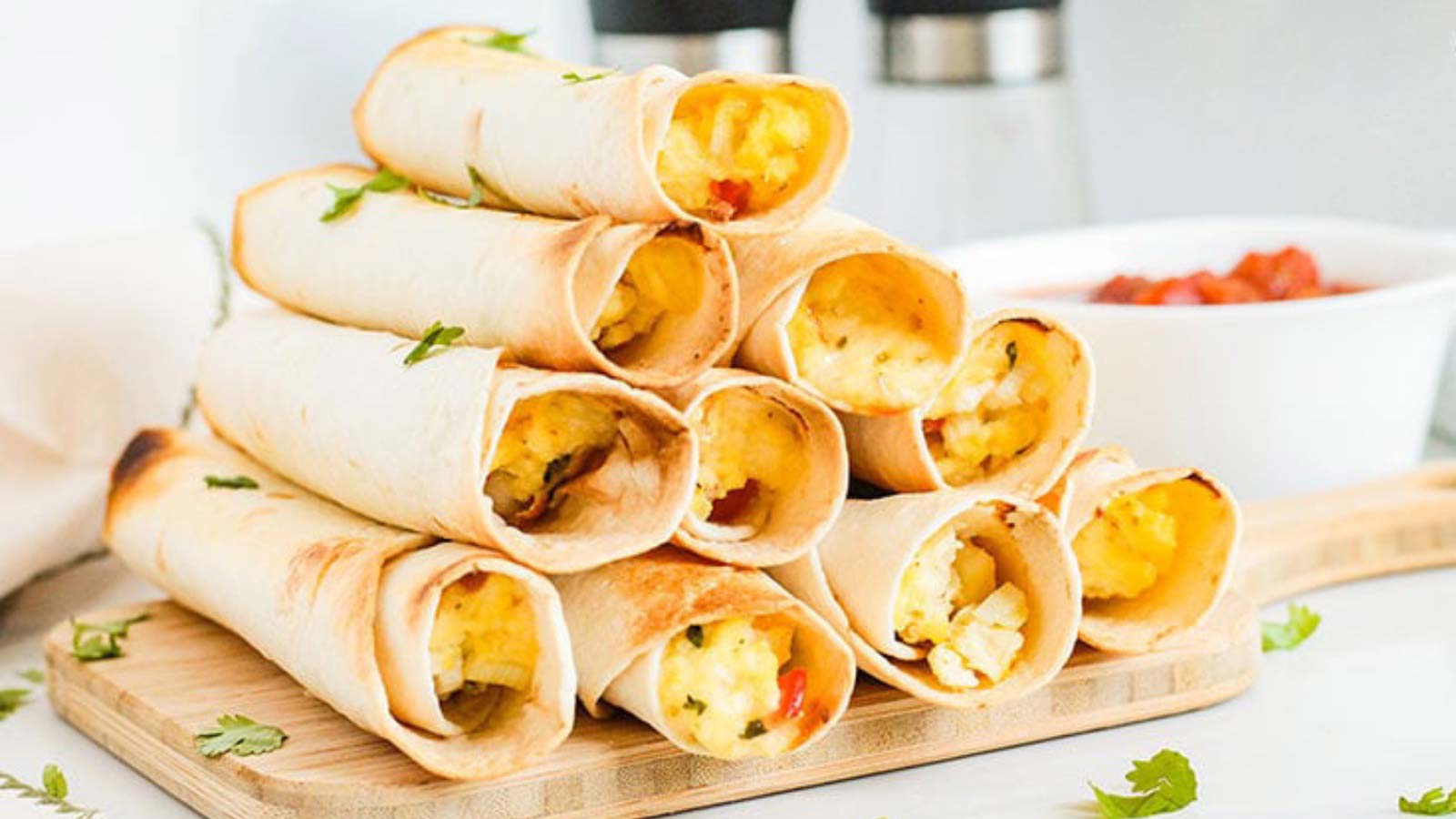 A stack of Healthy Breakfast Taquitos on a wood cutting board.