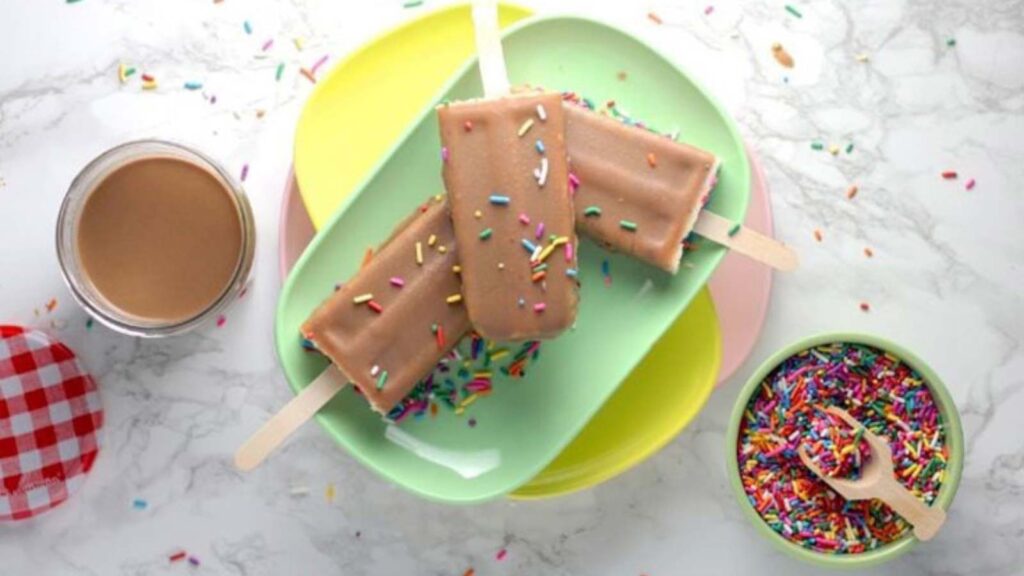 An overhead view of a plate holding three cakesicles with sprinkles.