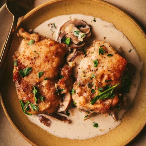 An overhead view of Champagne chicken on a plate with a fork.