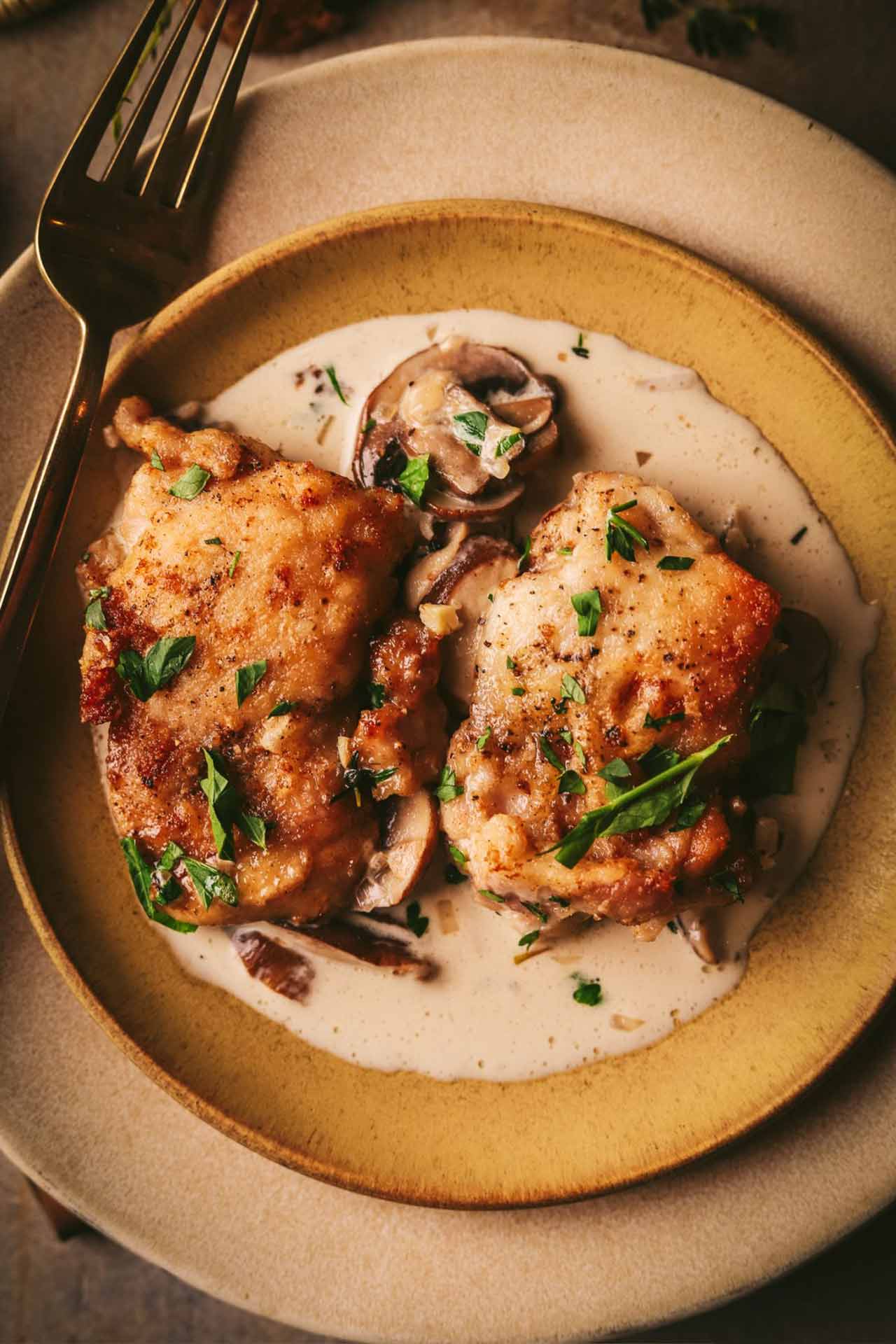 An overhead view of Champagne chicken on a plate with a fork.