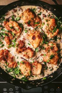 Fresh parsley sprinkled over the chicken in a pot of cream sauce.