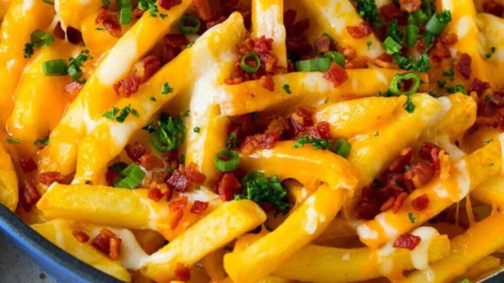 A closeup of cheese fries with bacon bits and chives.