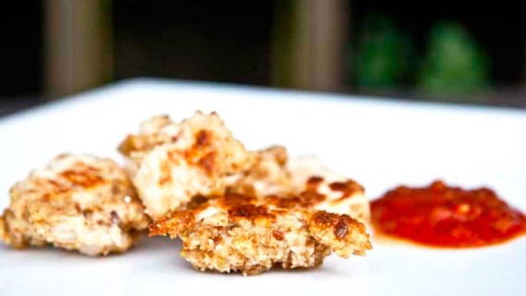 A white plate with chicken nuggets and a dollop of ketchup.