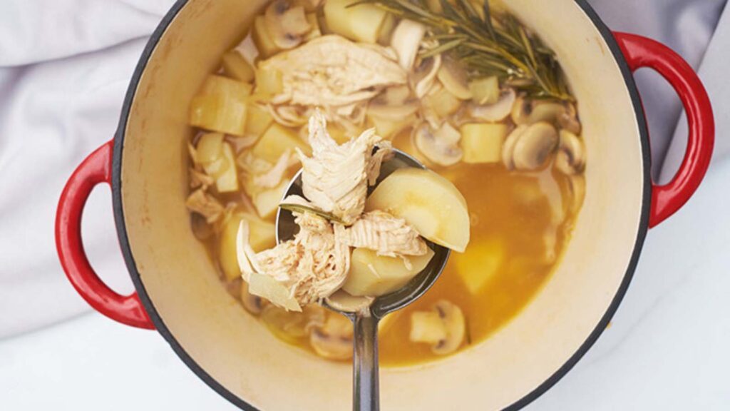 A ladle lifting Chicken Parsnip Soup out of a pot full of the soup.