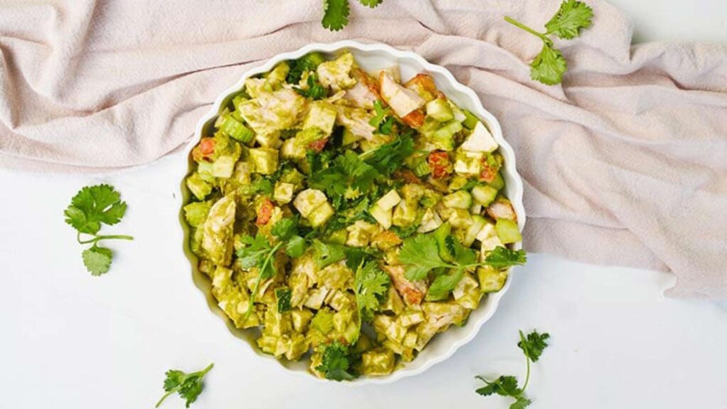 An overhead view of a white, fluted dish filled with chicken vegetable salad.