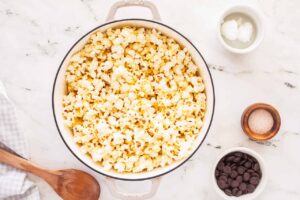 A white enamel pot filled with fresh popped popcorn.