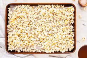 Popped popcorn spread out on a sheet pan.