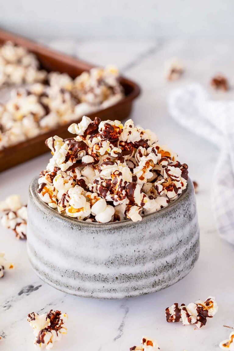 A gray bowl filled with Chocolate Popcorn and drizzled with chocolate.