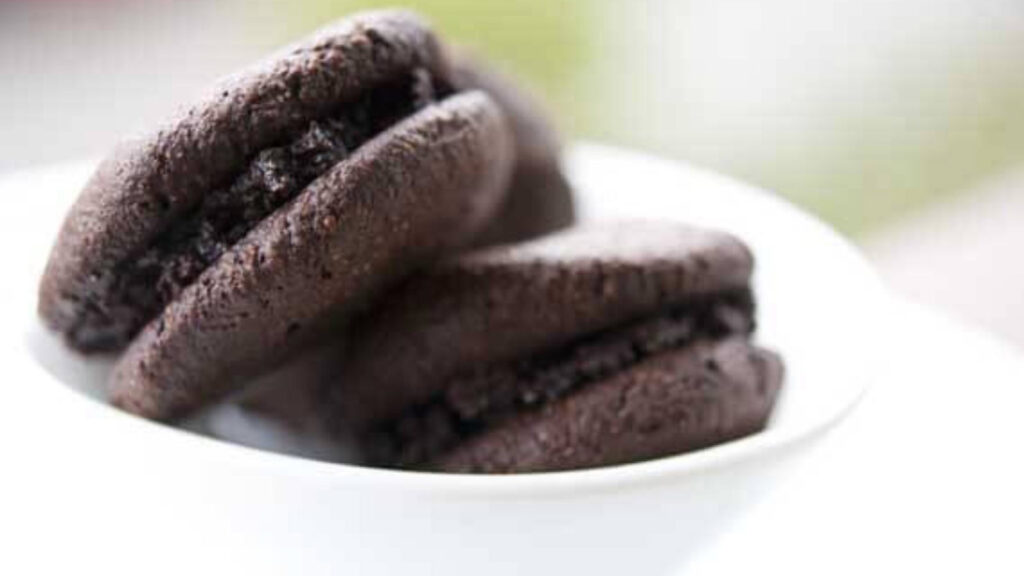 Two chocolate cookies in a white bowl.