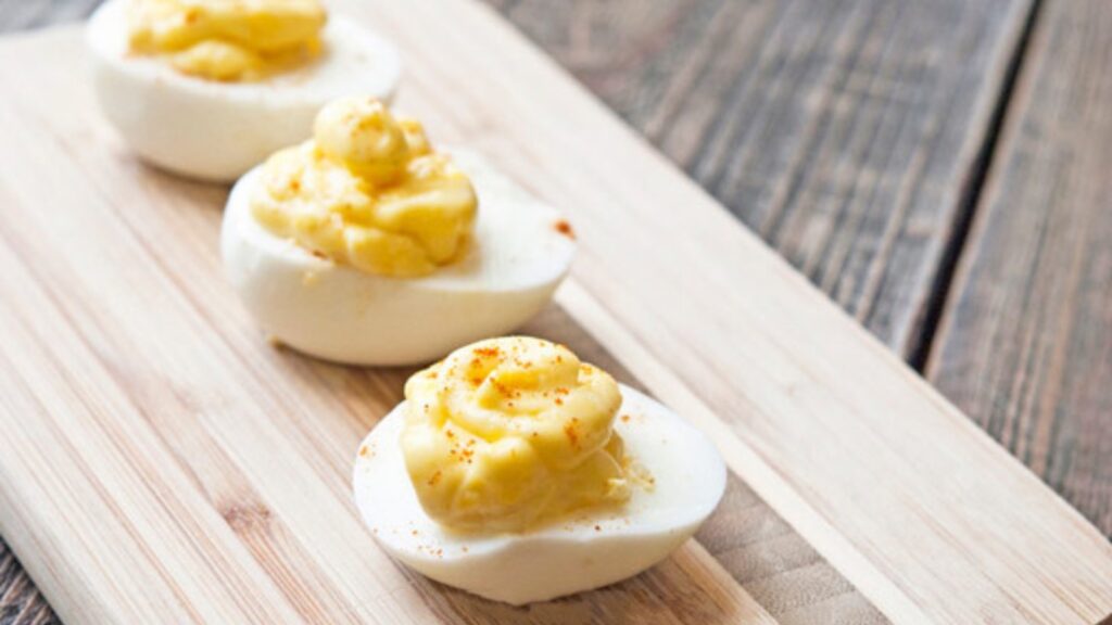 Three deviled eggs lined up on a small cutting board.