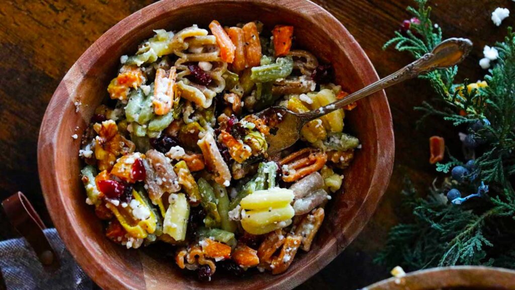 The finished Fall Harvest Pasta Salad sitting in a wooden bowl with a fork.