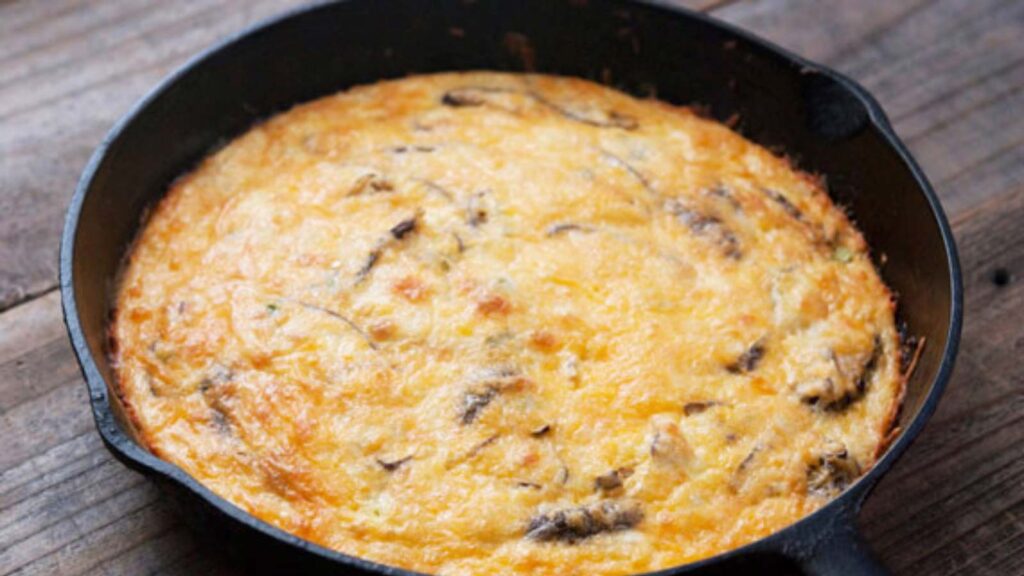 A Frittata in a cast iron skillet, sitting on a wood surface.