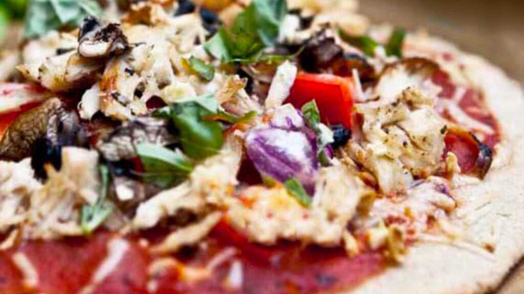 A closeup of a single Family Night Pizza on a wood surface.