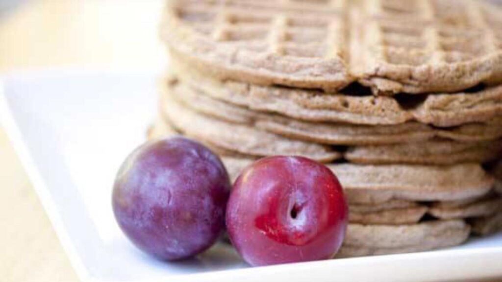 A stack of gingerbread waffles on a white, square plate.