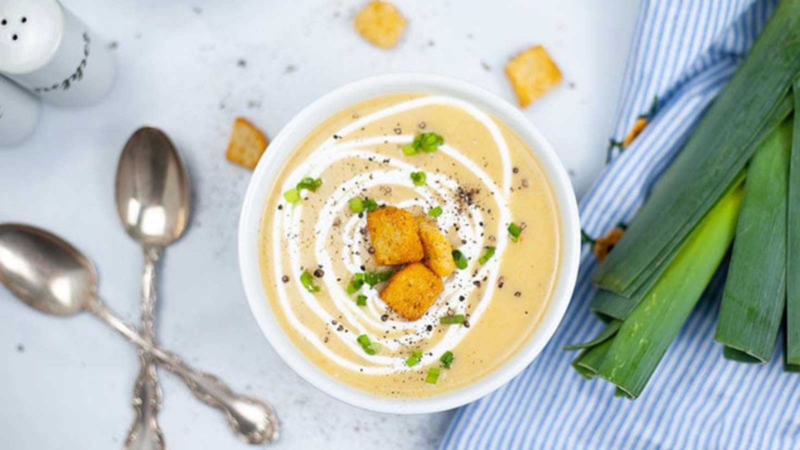 The finished Instant Pot Potato Leek Soup Recipe in a white bowl with croutons sprinkled on top.