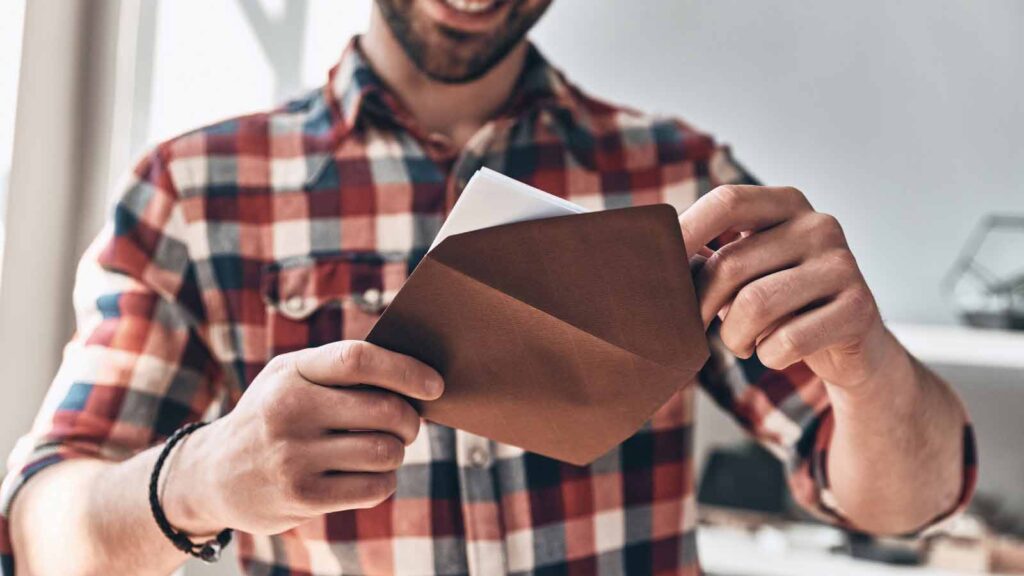 A smiling man opens an invitation.