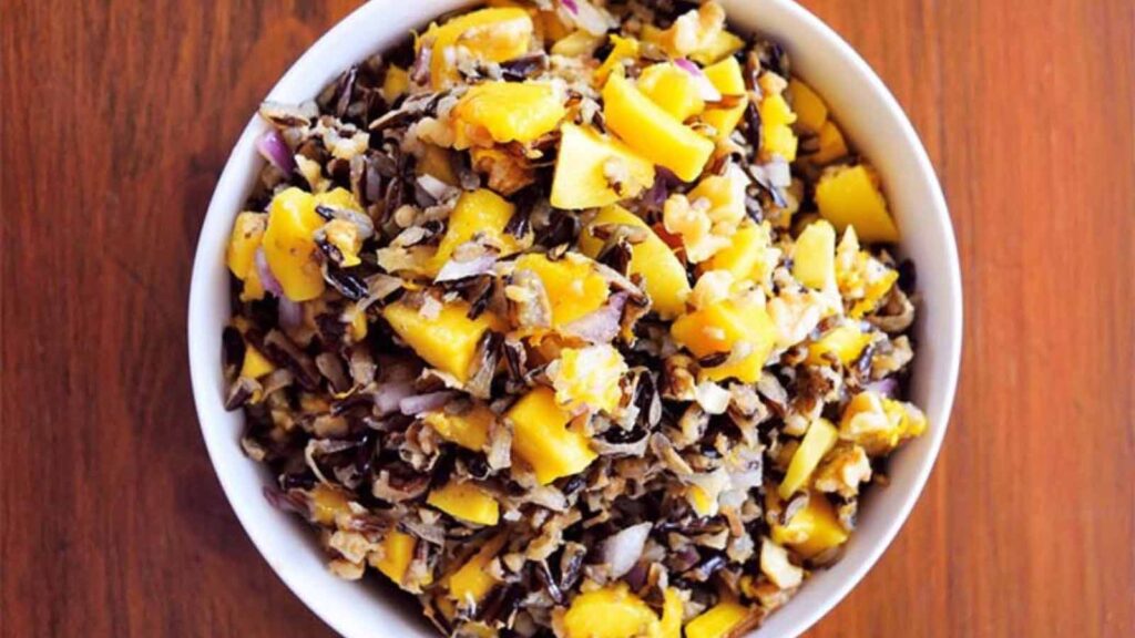 An overhead view of a white bowl filled with mango wile rice salad.