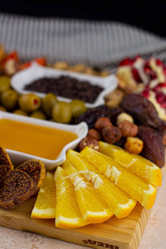 A front view of a Dessert Mezze Platter shows orange slices, figs, dates, nuts, and two bowls of dip.