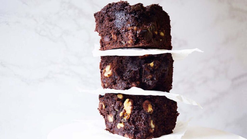 Three oat flour brownies stacked up on a white platter.