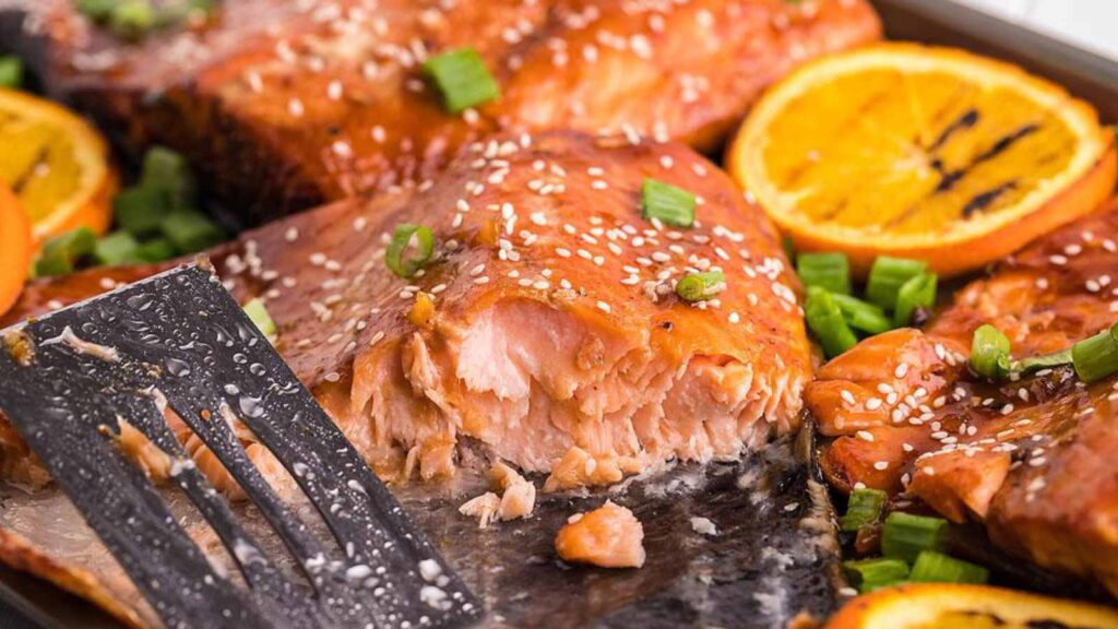 Orange bbq salmon filets on a baking sheet.