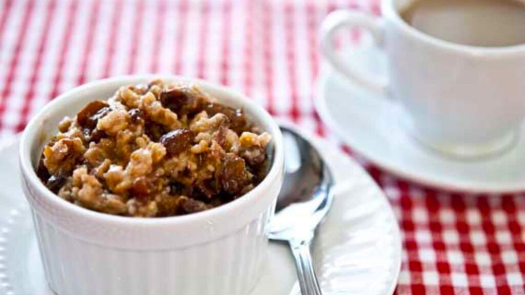 Slow Cooker Overnight Oatmeal in a white bowl with a cup of coffee next to it.