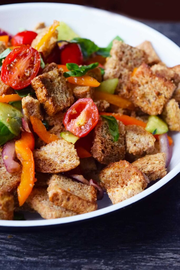 A font view of a white plate filled with Panzanella.