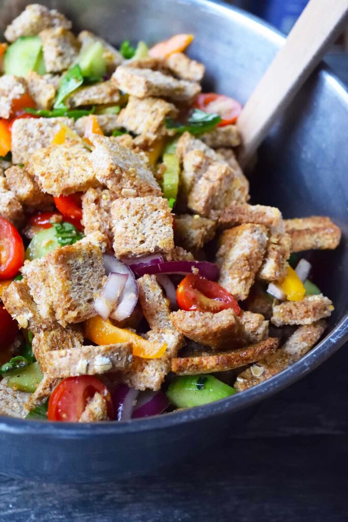 A side view of a mixing bowl filled with Panzanella.