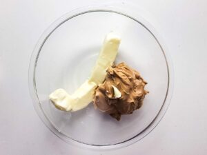 Butter and peanut butter in a glass mixing bowl.