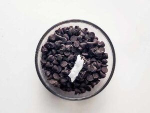 A bowl filled with chocolate chips and a small amount of coconut oil.