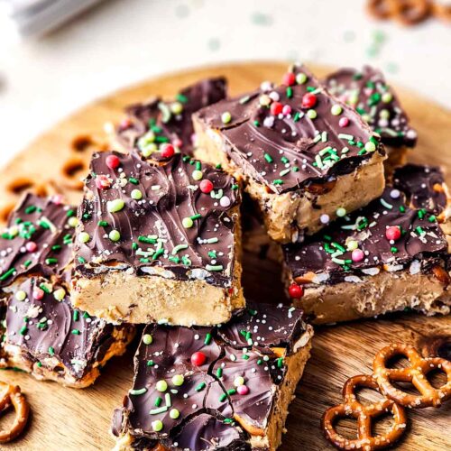 A side view of cut Peanut Butter Chocolate Bars served on a cutting board with a few pretzels.