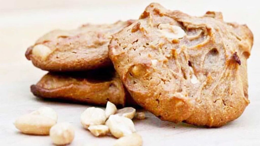 Three Peanut Butter Cookies laying on a wood cutting board.