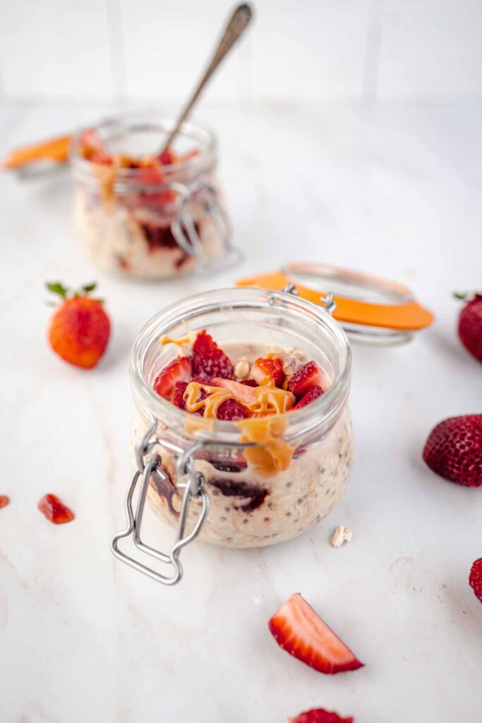 Two jars of Peanut Butter and Jelly Overnight Oats sitting on a white countertop.