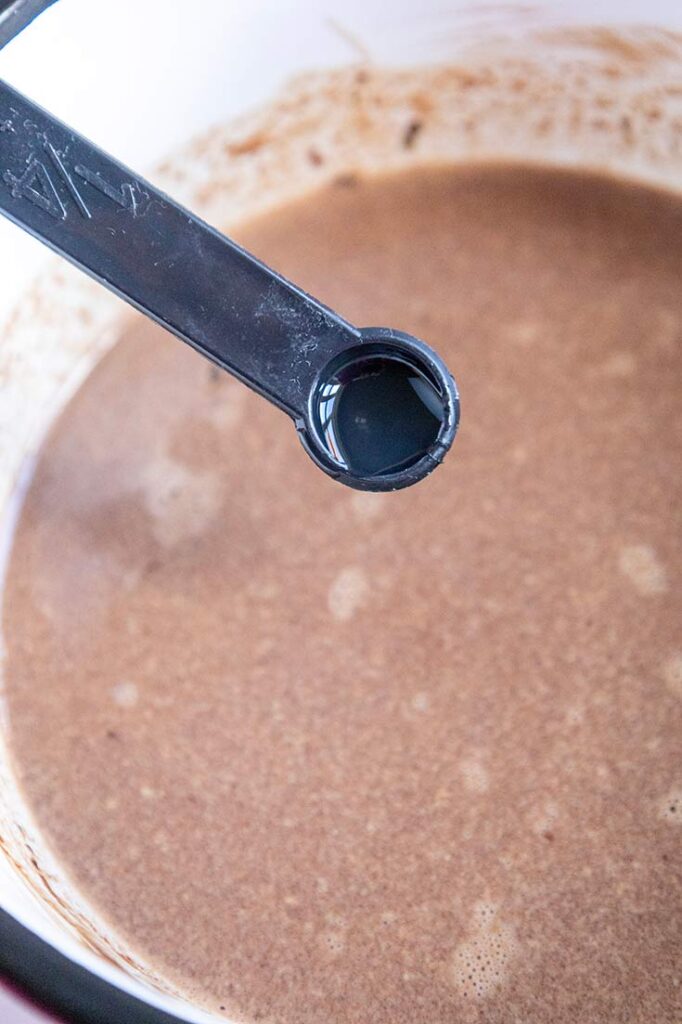 Adding peppermint extract to chocolate milk in a pot.
