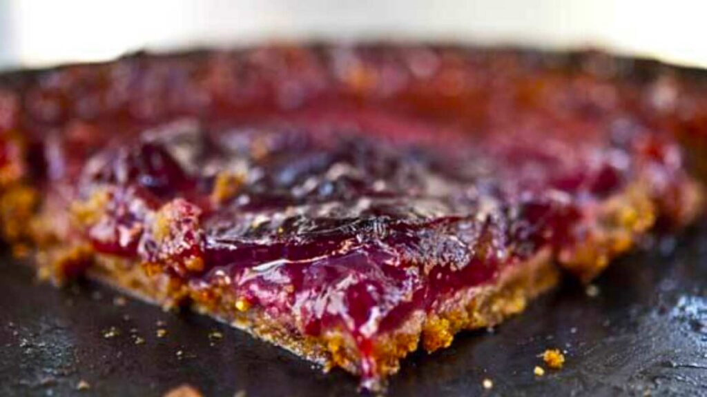 A slice of plum tart on a black pan.